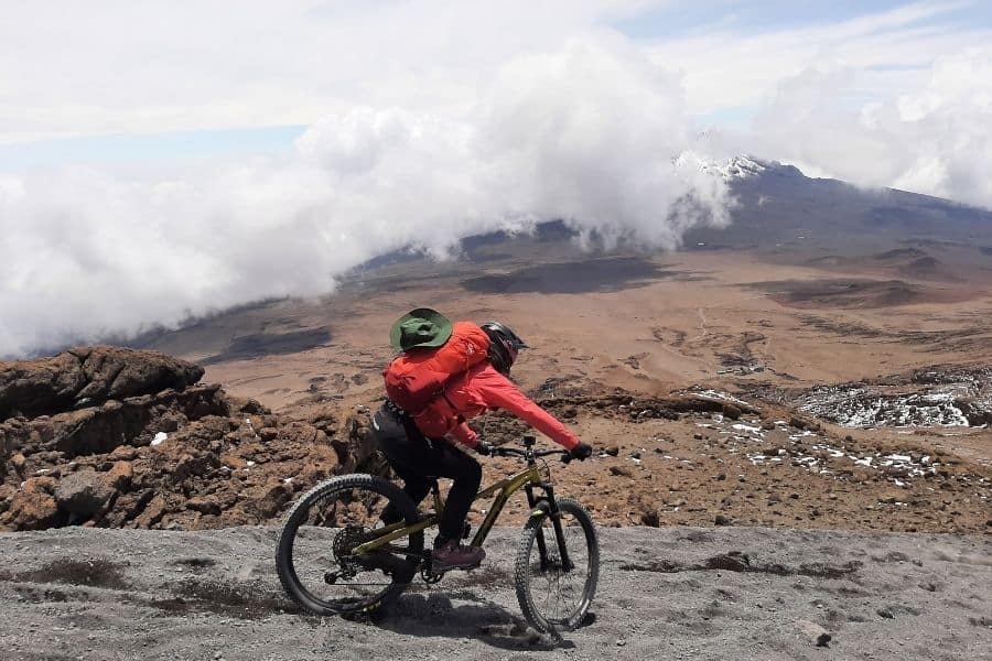 Una mujer poderosa montando una bicicleta de montaña en la cima de una montaña en África.