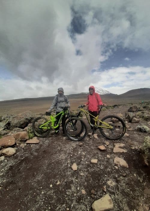 Dos mujeres ciclistas de montaña paradas una al lado de la otra en una zona rocosa de África.