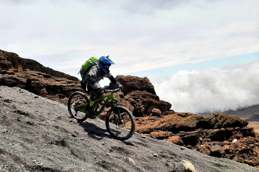Una mujer poderosa montando una bicicleta de montaña en una montaña rocosa de África.