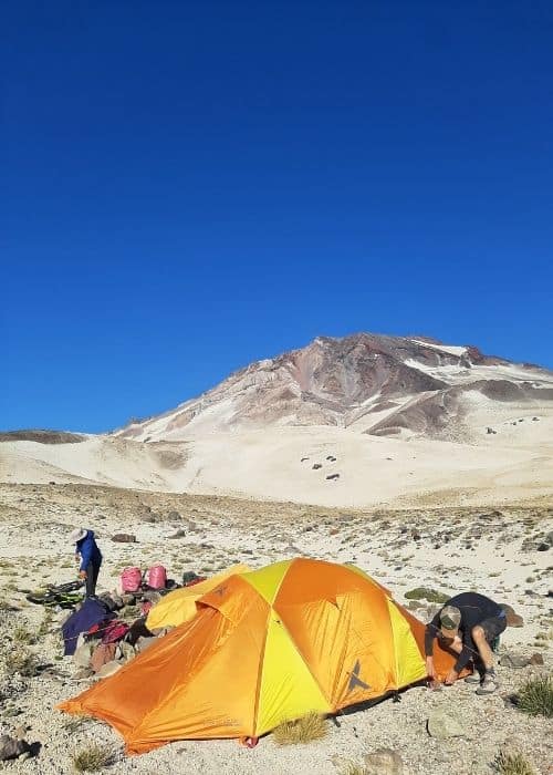 Un grupo de personas montando tiendas de campaña en el desierto, tomando un descanso de su paseo en bicicleta cerca de descabezado.