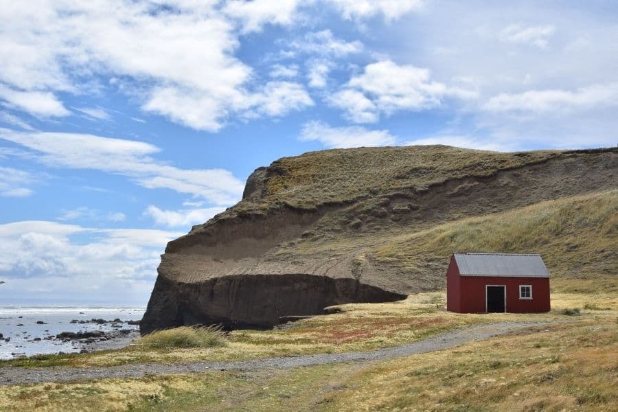 Una casa roja se encuentra al lado de un acantilado con vista al océano en la Patagonia.