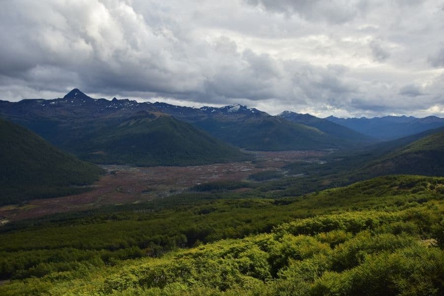 Una vista de un valle y montañas con nubes en el cielo en la Patagonia.