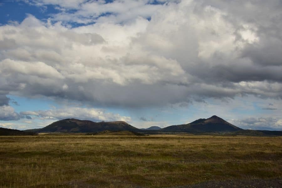 Un campo de hierba con montañas al fondo, bajo un cielo nublado en la Patagonia.