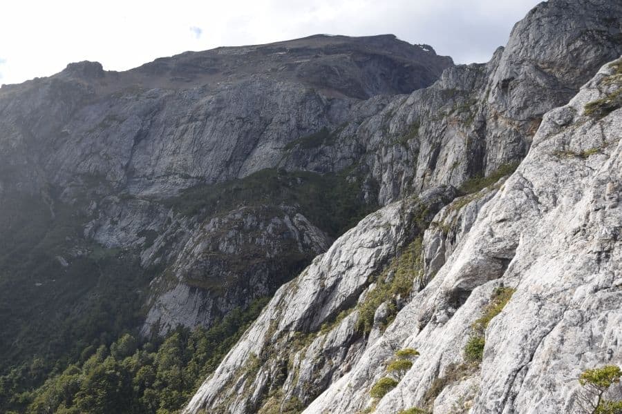 Un hombre se está embarcando en un primer ascenso por la ladera rocosa de una montaña en la Patagonia, abordando específicamente el desafiante terreno de La Muela.