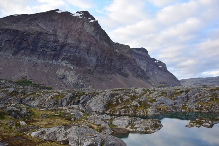 Una zona rocosa con un lago y montañas al fondo durante el primer ascenso en la Patagonia.