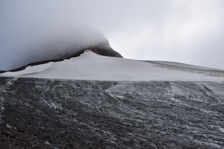 Una montaña cubierta de nieve con una nube al fondo en la Patagonia, posiblemente el icónico pico La Muela.