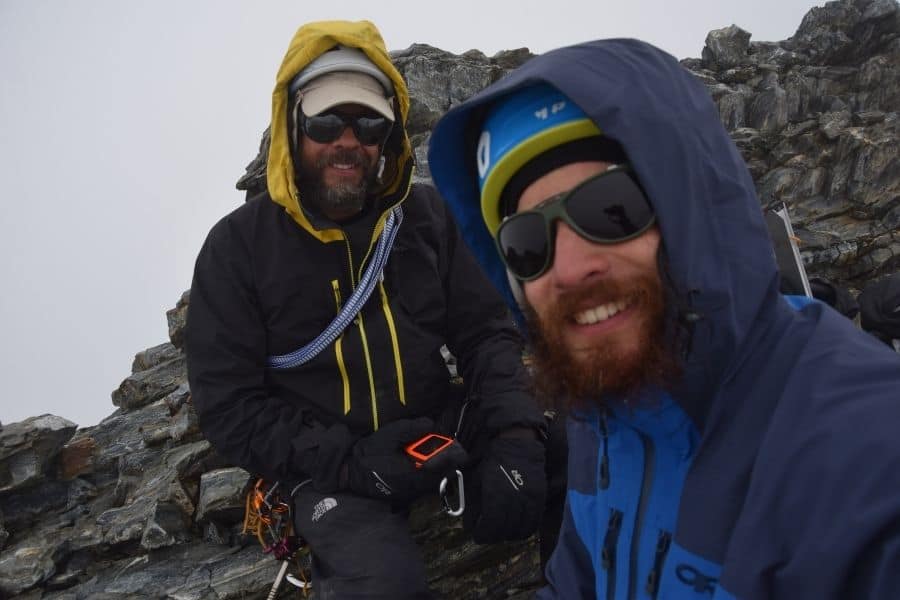 Dos hombres sonriendo en la cima de la montaña La Muela en la Patagonia después de su primer ascenso.