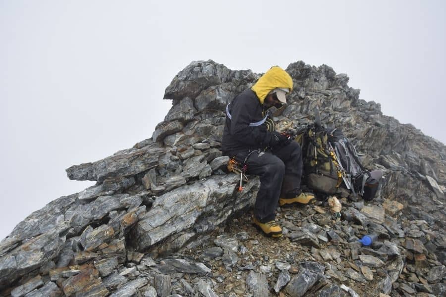 Un hombre sentado en la cima de una montaña rocosa en la Patagonia.