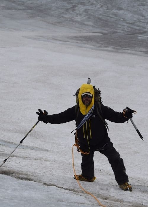 Un hombre vestido con una chaqueta amarilla esquía por una pendiente nevada en la Patagonia.