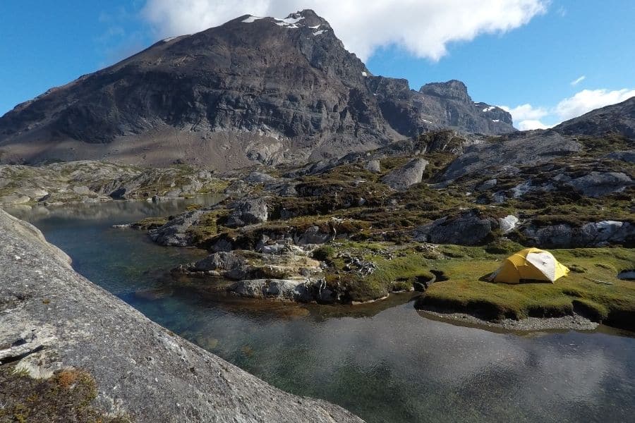 Una carpa amarilla se encuentra en la cima de La Muela, una montaña en la Patagonia, junto a un arroyo, marcando el primer ascenso de la zona.