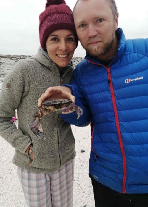 Un hombre y una mujer sosteniendo un cangrejo en la playa mientras disfrutan de un día en la playa.