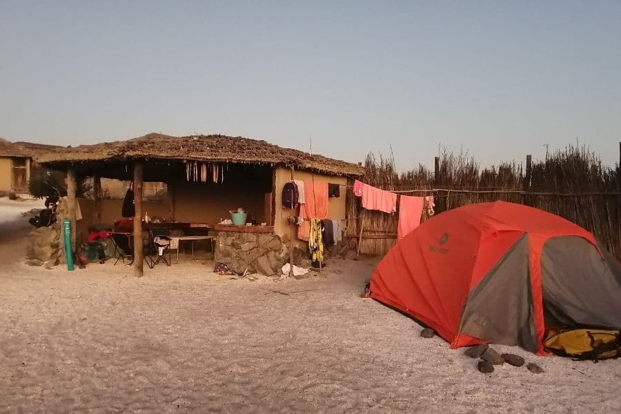 Se instala una carpa playero frente a una cabaña en la playa.