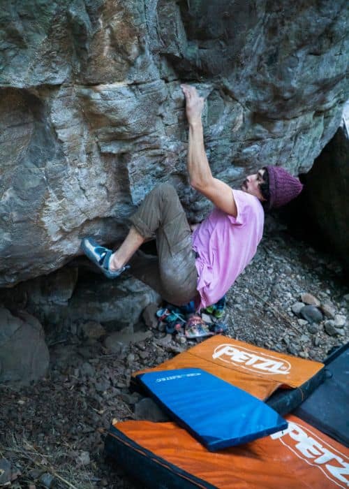 Benja Ayala está escalando una roca en el bosque, mostrando sus habilidades de escalada con calidad.