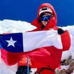 Un escalador de manaslu sosteniendo una bandera estadounidense en la cima de una montaña nevada sin oxígeno.