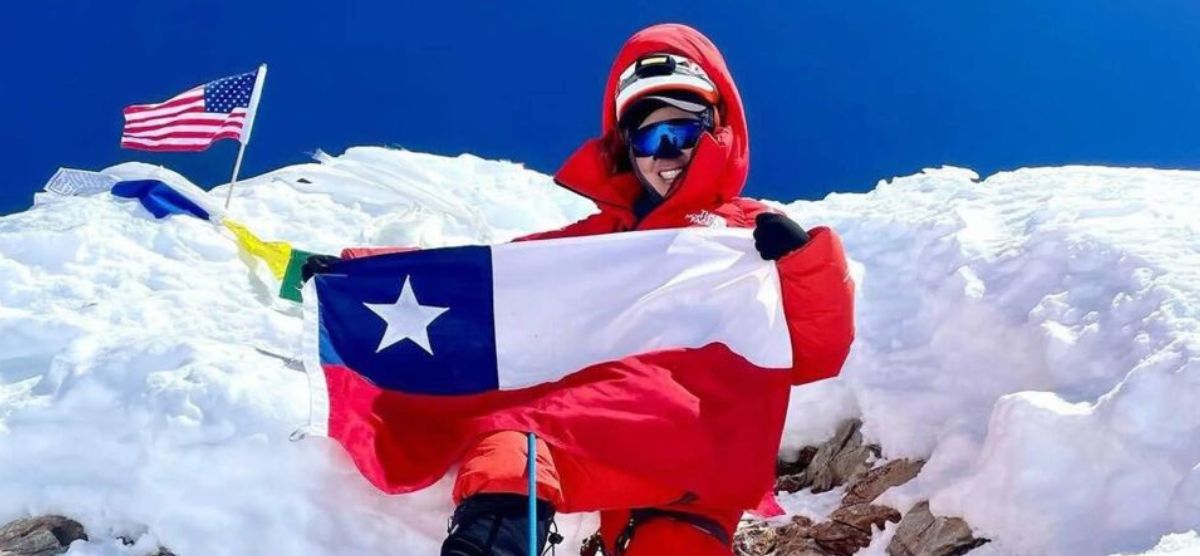 Un escalador de manaslu sosteniendo una bandera estadounidense en la cima de una montaña nevada sin oxígeno.