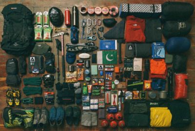 El contenido de una mochila llena de equipo de trekking dispuesto sobre un suelo de madera.